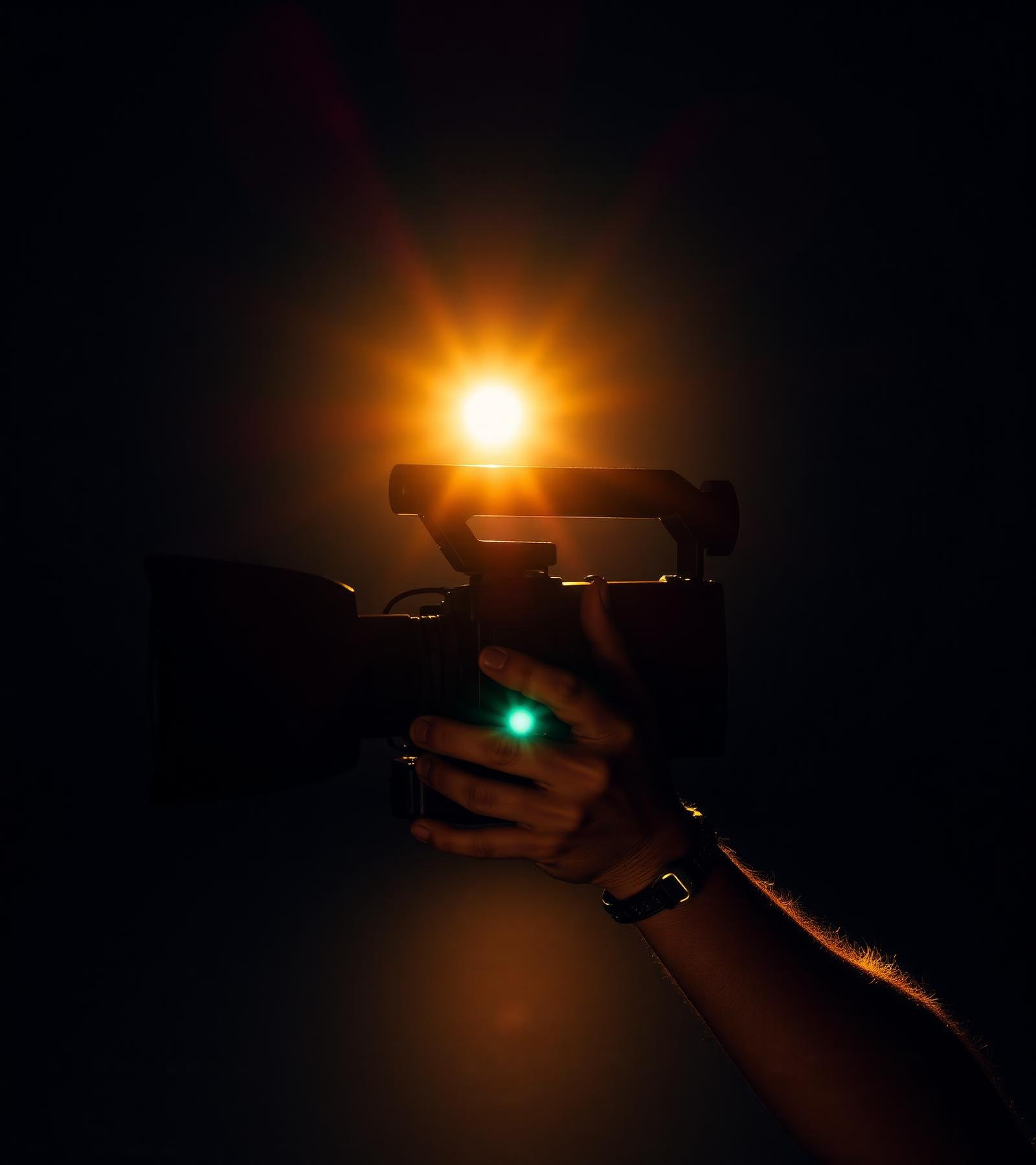 Cinematographer holding a cinema camera against a warm ember light